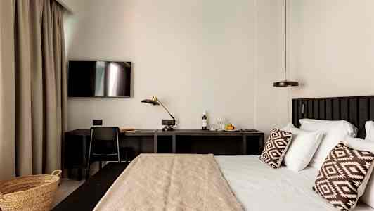 Hotellihuone, jossa on sänky, työpöytä ja televisio. (Tekoälyn luoma teksti)