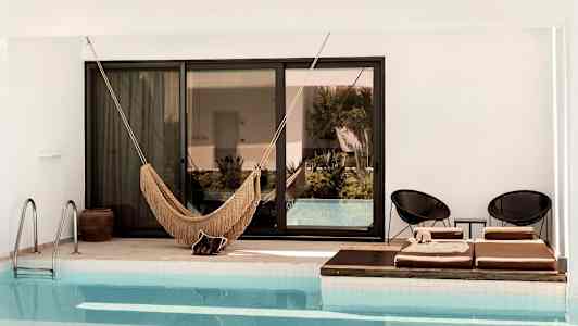 Kuva uima-altaasta, jossa on riippumatto ja aurinkotuoleja reunalla. (Tekoälyn luoma teksti)