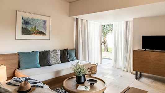 Modernisti sisustettu olohuone, jossa on sohva, sohvapöytä, televisio ja suuret lasiovet ulos. (Tekoälyn luoma teksti)