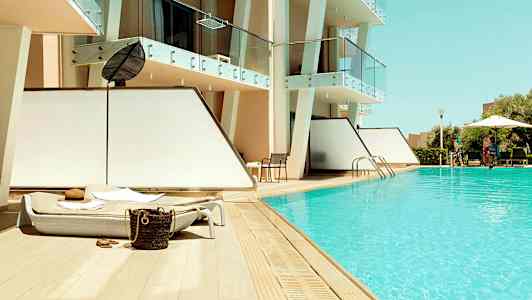 Ulkouima-allas aurinkotuoleilla modernin hotellin vieressä. (Tekoälyn luoma teksti)