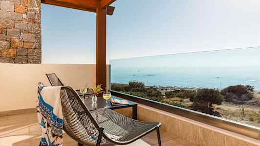 Terassi, josta on näkymä merelle, huonekalut ja juomia pöydällä. (Tekoälyn luoma teksti)