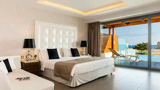 Hotellihuone, jossa on parivuode, päivävuode ja näkymä terassille, jolla on uima-allas ja meri. (Tekoälyn luoma teksti)