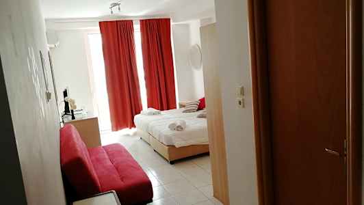 Hotellihuone, jossa on pedattu sänky, punaiset verhot ja punainen sohva. (Tekoälyn luoma teksti)