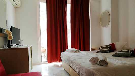 Hotellihuone, jossa on parisänky, punaiset verhot ja televisio lipaston päällä. (Tekoälyn luoma teksti)