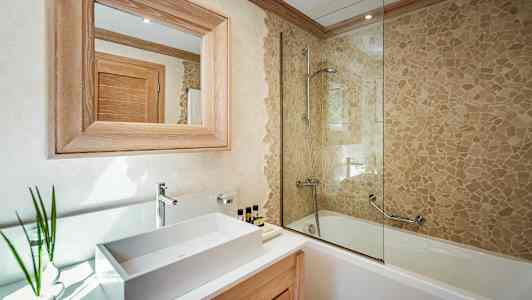 Kylpyhuone, jossa pesuallas, puukehyksinen peili ja kylpyamme mosaiikkiseinällä ja suihkulla. (Tekoälyn luoma teksti)