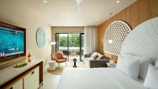 Tyylikäs hotellihuone, jossa on suuri sänky, oleskelualue ja parveke, jolta on näkymä vehreyteen. (Tekoälyn luoma teksti)