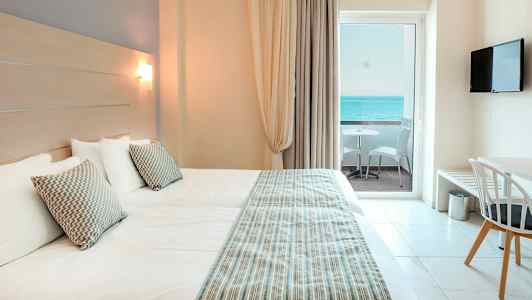 Hotellihuone, jossa kaksi vuodetta, näkymä merelle parvekkeelta. (Tekoälyn luoma teksti)