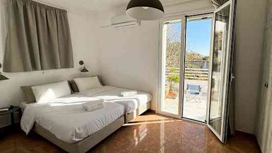 Hotellihuone, jossa kaksi erillistä vuodetta, avoimet ikkunat näkymällä terassille. (Tekoälyn luoma teksti)