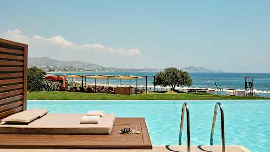 Näkymä uima-altaalta merelle, aurinkotuoleja ja varjoja. (Tekoälyn luoma teksti)