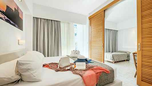 Hotellihuone, jossa on kaksi sänkyä, koristeltu henkilökohtaisilla esineillä etummaisella sängyllä. (Tekoälyn luoma teksti)