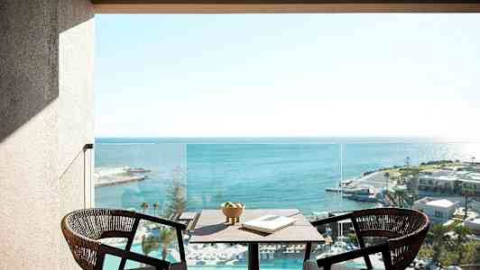 Kaksi tuolia ja pöytä, jolla on kulho ja kirja, ovat parvekkeella, josta on näkymä merelle. (Tekoälyn luoma teksti)