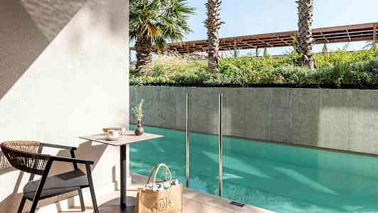 Istuinryhmä, jossa pöytä ja tuoli, altaan vieressä lasikaide. (Tekoälyn luoma teksti)