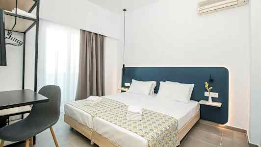 Moderni hotellihuone, jossa kaksi pedattua yhden hengen vuodetta, kirjoituspöytä ja tuoli sekä seinään kiinnitetty ilmastointilaite. (Tekoälyn luoma teksti)