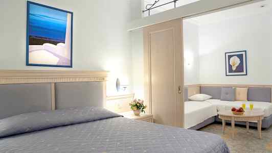 Hotellihuone, jossa on kaksi sänkyä ja oleskelutila, koristeltu kukilla ja maalauksilla. (Tekoälyn luoma teksti)