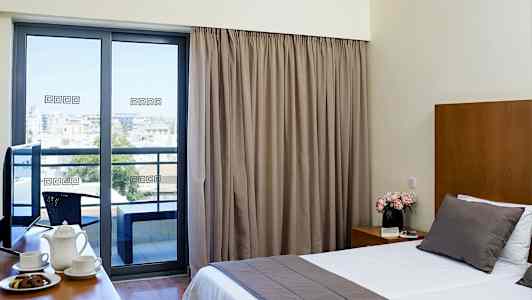 Hotellihuone, jossa suuri sänky, kahvikuppeja pöydällä ja parveke näkymällä. (Tekoälyn luoma teksti)