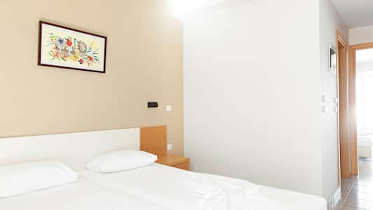 Hotellihuone, jossa on kaksi vuodetta, yöpöytä ja maalaus seinällä. (Tekoälyn luoma teksti)