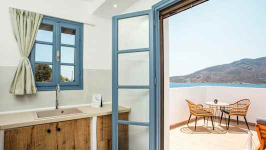 Keittiö, jossa on siniset ikkunat ja avoin ovi parvekkeelle, josta on näkymä merelle. (Tekoälyn luoma teksti)