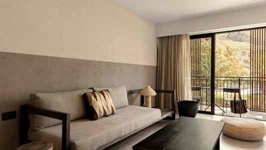 Olohuone, jossa on sohva, sohvapöytä ja suuret ikkunat parvekkeelle päin. (Tekoälyn luoma teksti)