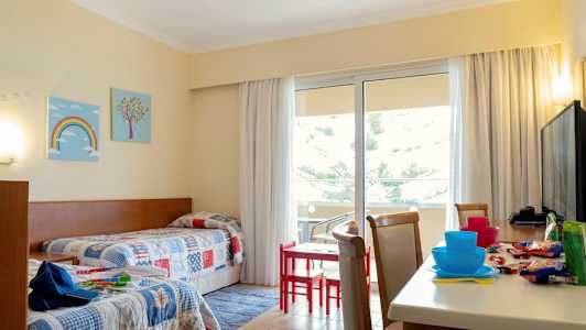 Hotellihuone, jossa kaksi yhden hengen vuodetta ja pöytä tuoleineen lähellä parveketta. (Tekoälyn luoma teksti)