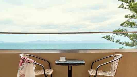 Kaksi tuolia pöydän ääressä terassilla merinäköalalla. (Tekoälyn luoma teksti)