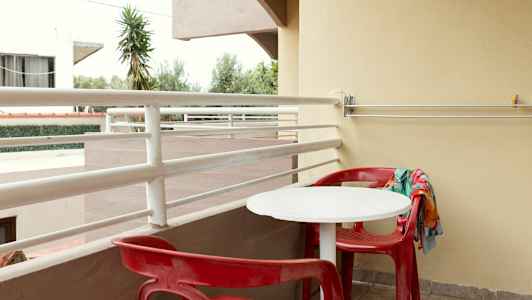 Parveke, jossa punaiset tuolit ja valkoinen pöytä. (Tekoälyn luoma teksti)