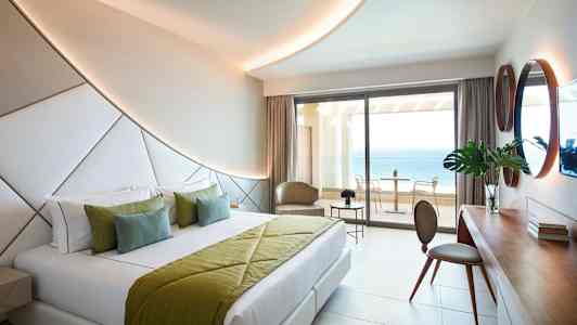 Nykyaikainen hotellihuone, jossa parivuode ja näkymä merelle parvekkeelta. (Tekoälyn luoma teksti)