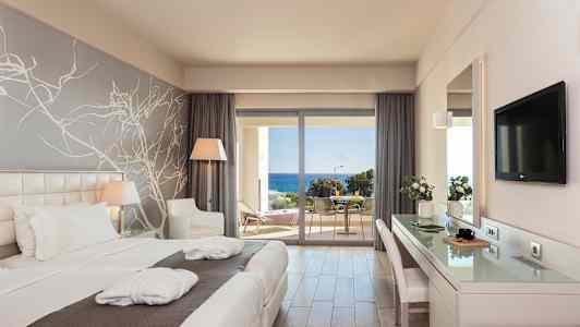 Hotellihuone, jossa on kaksi yhden hengen vuodetta, kirjoituspöytä, istumapaikka ja ikkuna parvekkeelle merinäköalalla. (Tekoälyn luoma teksti)