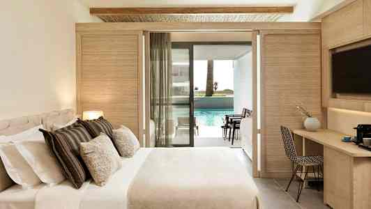 Hotellihuone, jossa sänky, työpöytä ja parveke, joka johtaa uima-altaalle. (Tekoälyn luoma teksti)