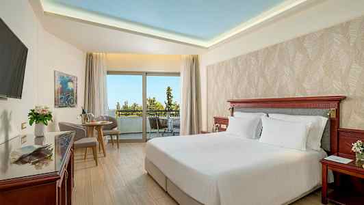 Hotellihuone, jossa on parivuode, istuinryhmä ja suuri parveke näkymällä. (Tekoälyn luoma teksti)