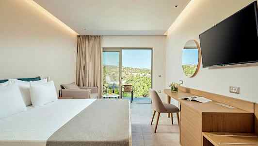 Moderni hotellihuone, jossa on parivuode, kirjoituspöytä ja tuoli sekä parveke näköalalla vehreään maastoon. (Tekoälyn luoma teksti)