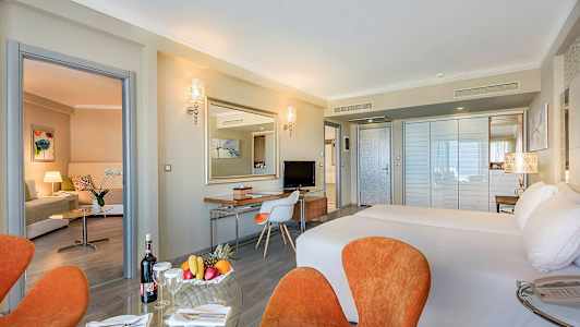 Hotellihuone, jossa parivuode, istuma-alue ja työpöytä. (Tekoälyn luoma teksti)