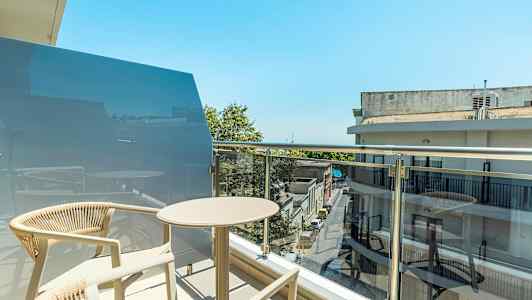 Parveke, jossa pöytä ja tuolit kaupunkiympäristössä. (Tekoälyn luoma teksti)