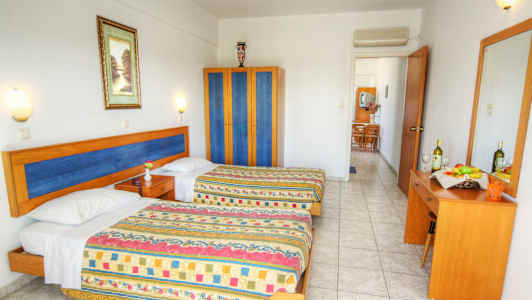 Hotellihuone, jossa on kaksi sänkyä, vaatekaappi ja lipasto peilillä. (Tekoälyn luoma teksti)