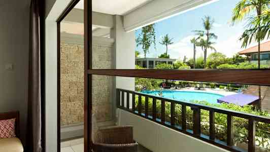 Parveke näkymällä allasalueelle, ulkokalusteita ja vihreää ympäristöä. (Tekoälyn luoma teksti)