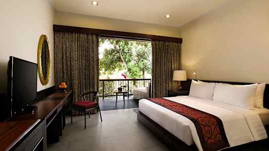 Hotellihuone, jossa on iso sänky, kirjoituspöytä kultakehyksisellä peilillä ja televisio. Ikkuna avautuu parvekkeelle, josta on näkymä viheralueelle. (Tekoälyn luoma teksti)