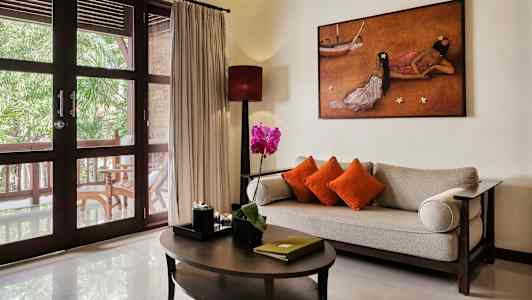 Olohuone, jossa sohva, pöytä ja koristeluja suurten lasiovien edessä, jotka johtavat kuistille. (Tekoälyn luoma teksti)