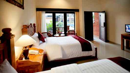 Hotellihuone, jossa on kaksi sänkyä, iso ikkuna ja kaksi tuolia pienellä pöydällä edessä. (Tekoälyn luoma teksti)