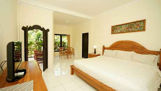 Tyylikkäästi sisustettu ja valoisa makuuhuone, jossa suuri sänky, puukoristeita ja istuinalue ikkunan ääressä, josta on näkymä vehreyteen. (Tekoälyn luoma teksti)