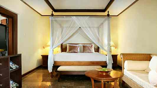 Makuuhuone, jossa on sänky katosvuoteella, kaksi yöpöytää ja pieni sohva pöydän edessä. (Tekoälyn luoma teksti)