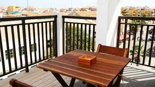 Näkymä parvekkeelta, jossa on puupöytä ja tuolit. (Tekoälyn luoma teksti)