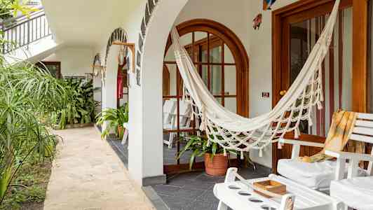 Ulkoalue, jossa valkoisia tuoleja, riippumatto ja vihreitä kasveja. (Tekoälyn luoma teksti)