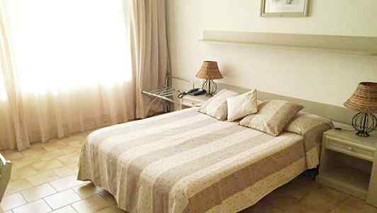 Hotellihuone, jossa on parivuode, kaksi yöpöytää ja lampunvarjostin. (Tekoälyn luoma teksti)