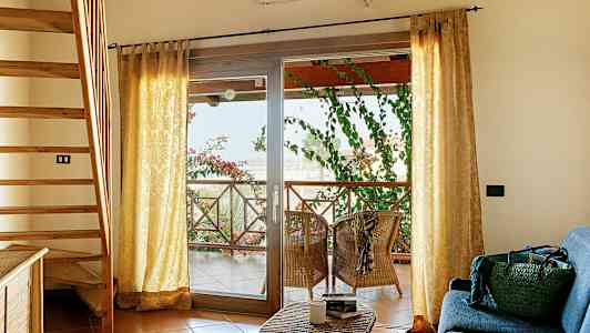 Sisätilat, jossa portaat, sohvakulmaus ja terassi istuimineen ja vihreine kasveineen. (Tekoälyn luoma teksti)