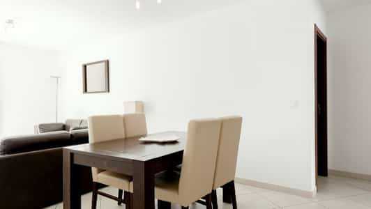 Nykyaikaisesti sisustettu olohuone, etualalla ruokapöytä ja tuolit. (Tekoälyn luoma teksti)