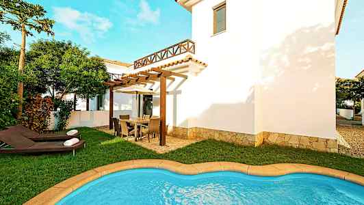 Kuva villasta, jossa on pieni uima-allas, nurmikko ja ulkokalusteita tilavalla terassilla. (Tekoälyn luoma teksti)