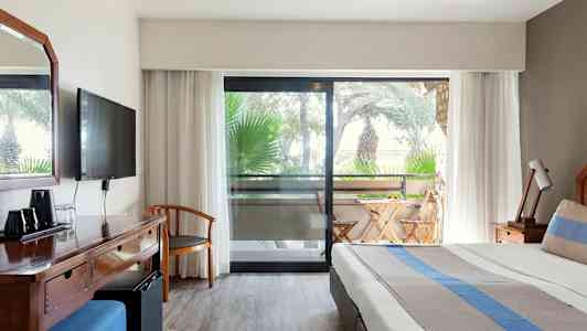 Kuva hotellihuoneesta, jossa on sänky, kirjoituspöytä ja parveke ulkokalusteineen. (Tekoälyn luoma teksti)