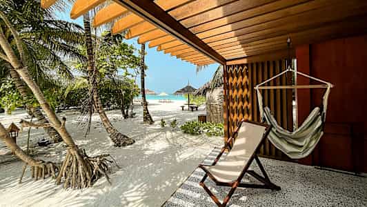 Terassi riippukeinulla ja aurinkotuolilla, näkymä hiekkarannalle ja palmuille. (Tekoälyn luoma teksti)