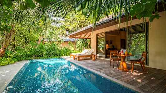 Yksityinen uima-allas trooppisen huvilan vieressä, jossa on aurinkotuoli ja pöytä tuoleineen. (Tekoälyn luoma teksti)