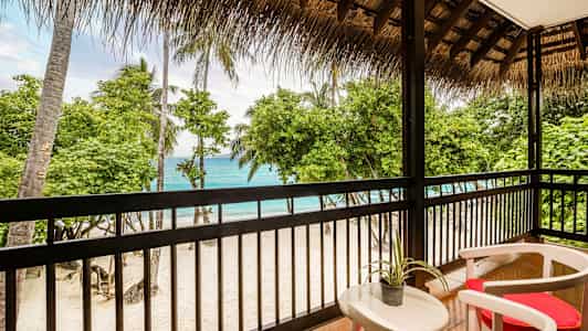 Näkymä terassilta hiekkarannalle, jossa palmuja ja meri. (Tekoälyn luoma teksti)