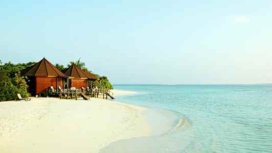 Bungaloweja hiekkarannalla kirkasvetisen meren äärellä. (Tekoälyn luoma teksti)